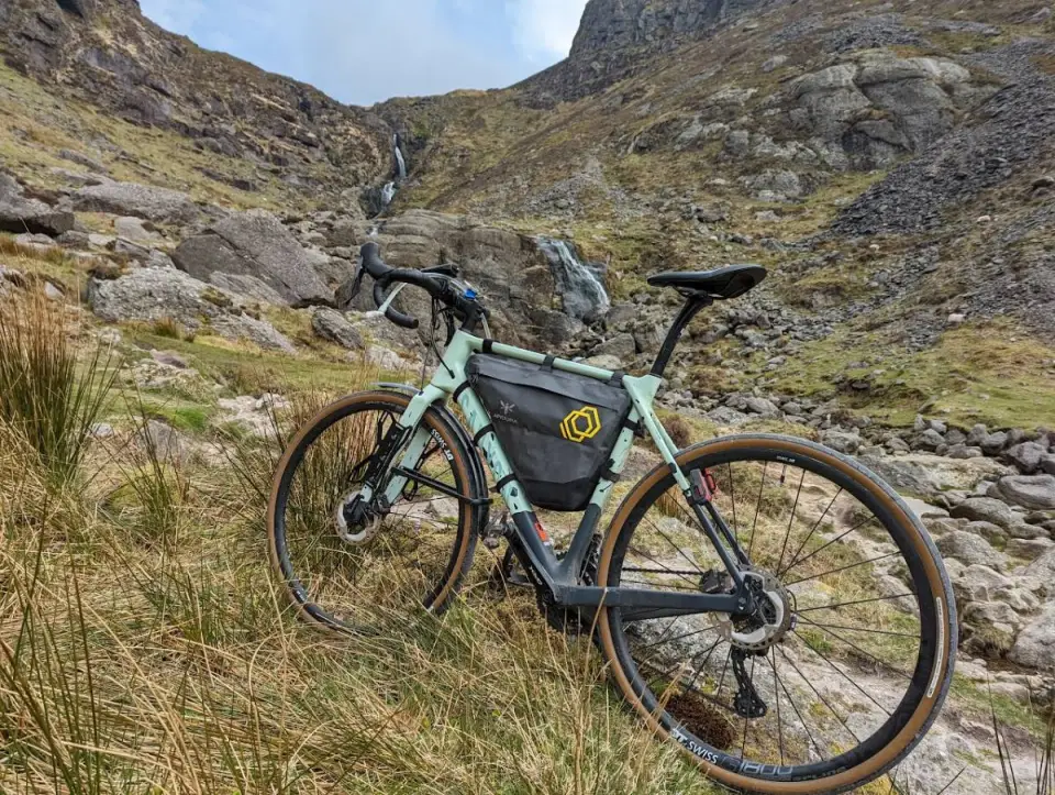 A gravel bike in the grass below the Mahon Falls waterfall