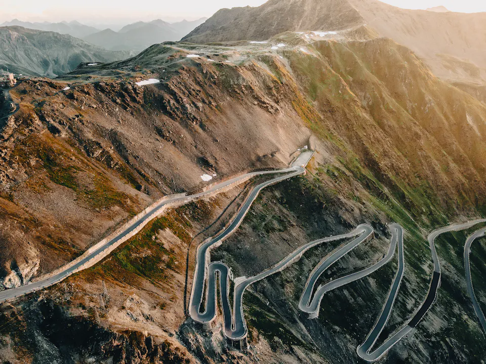 A mountain road winding in tight hairpins down a valley