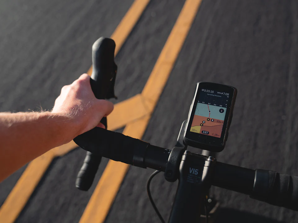 A rider's hands on the handlebars with a GPS unit mounted in the middle