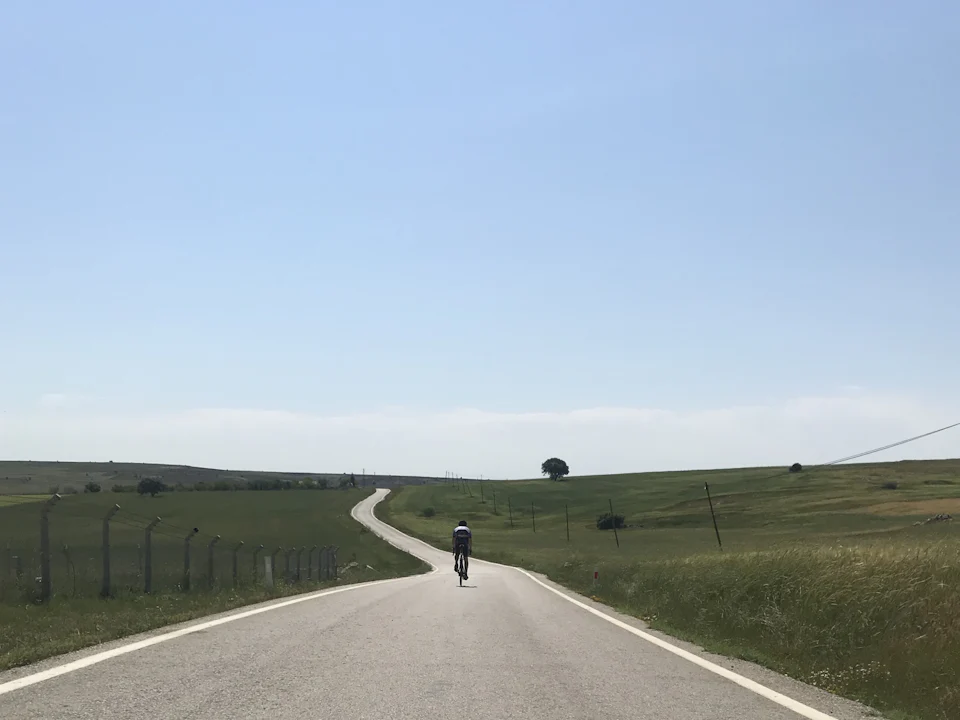 A lone cyclist on a long, empty road through open country