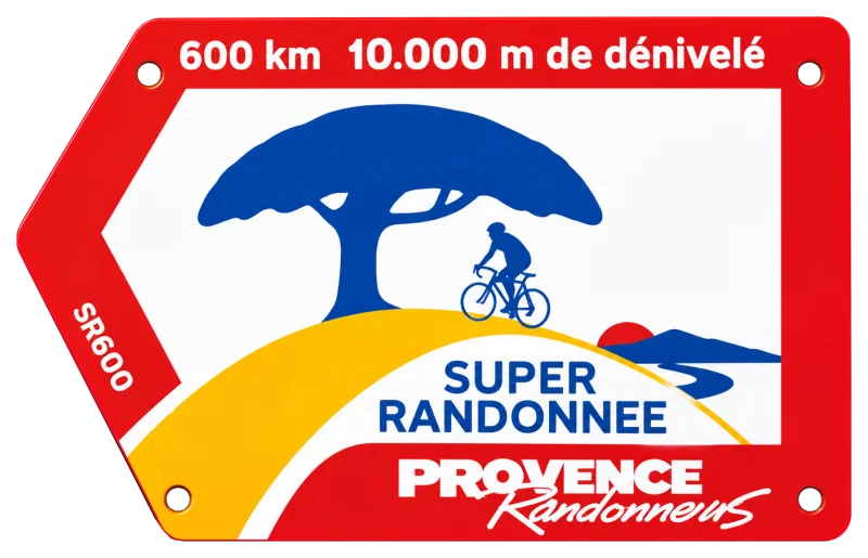 The Super Randonnée frame plate from Provence Randonneurs: “600 km, 10.000 m de dénivelé” over a rider beneath a blue pine